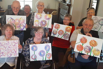 group of clients showing off their paintings of flowers