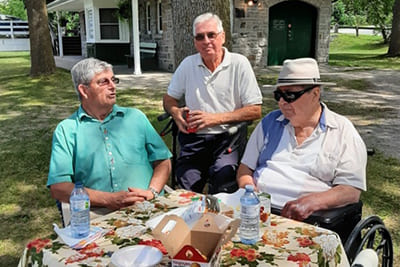 three men sitting around a table outside of BDH